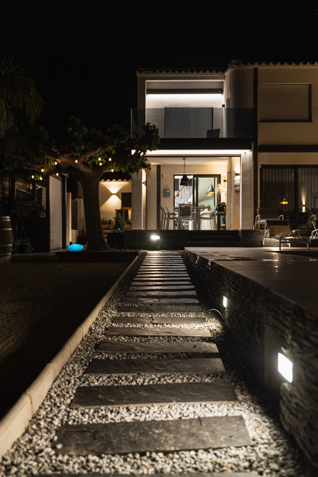 Façade de la villa et allée d'accès éclairée de nuit