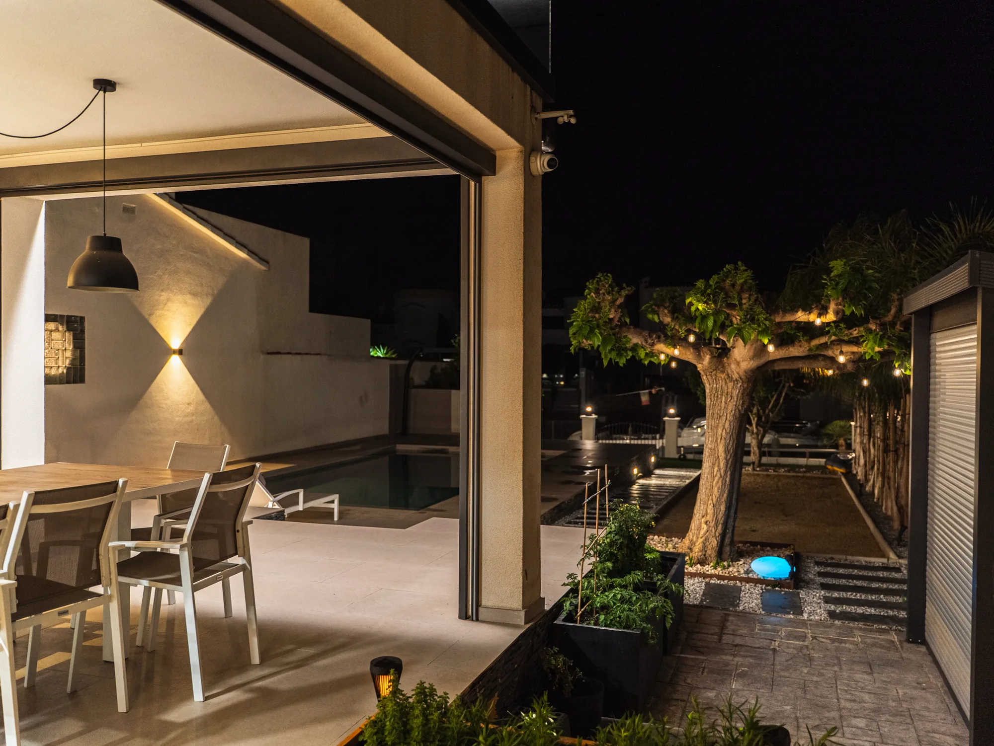 Terrasse couverte et coin salon extérieur de la villa, en soirée