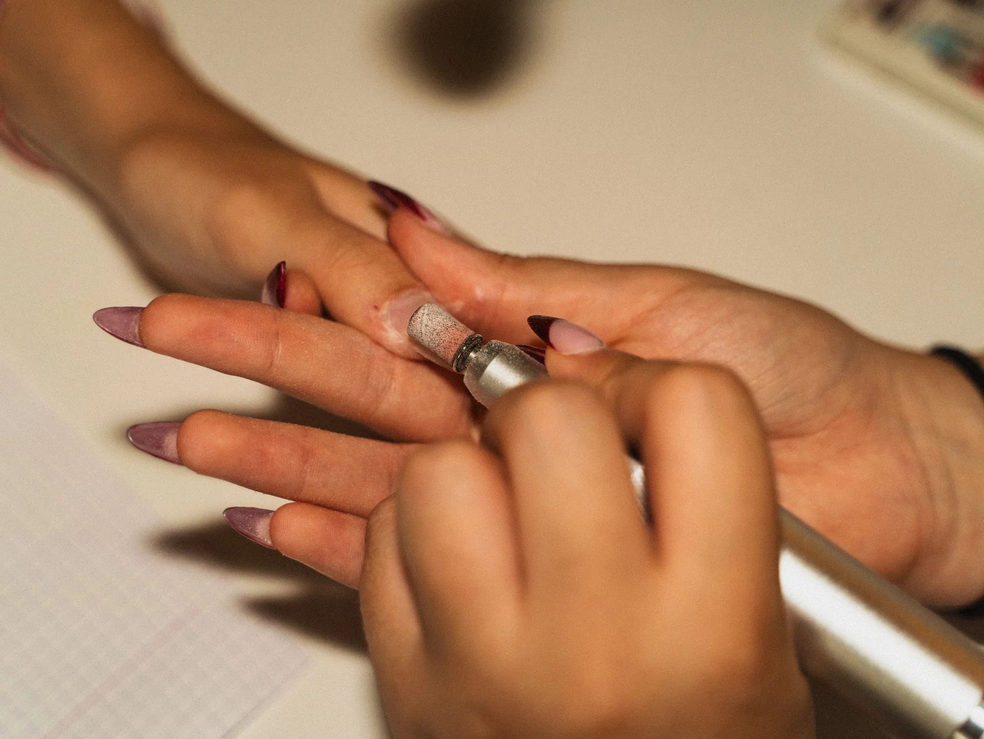 Limage et mise en forme d'ongles almond vernis bordeaux, en cours de prestation