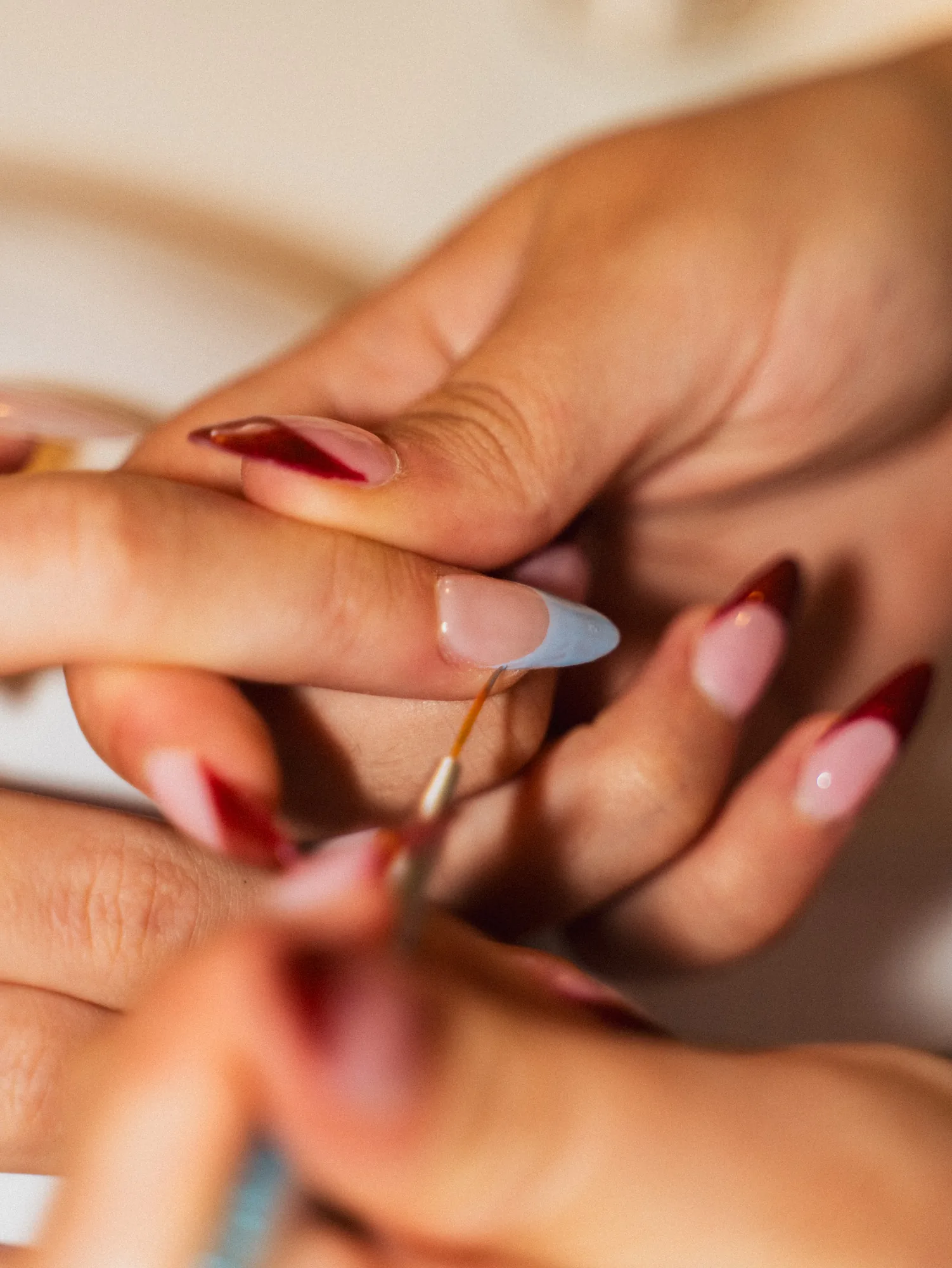 Pose au pinceau d'un vernis bleu ciel sur un ongle almond