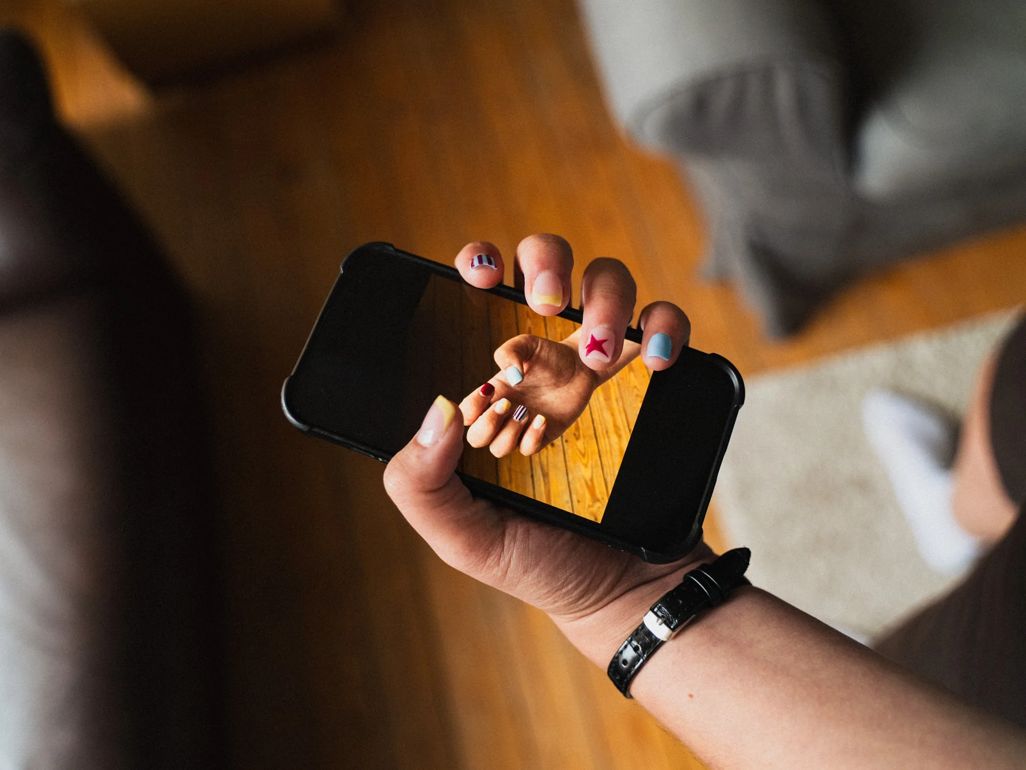 Reflet dans l'écran d'un smartphone mettant en valeur des ongles multicolores