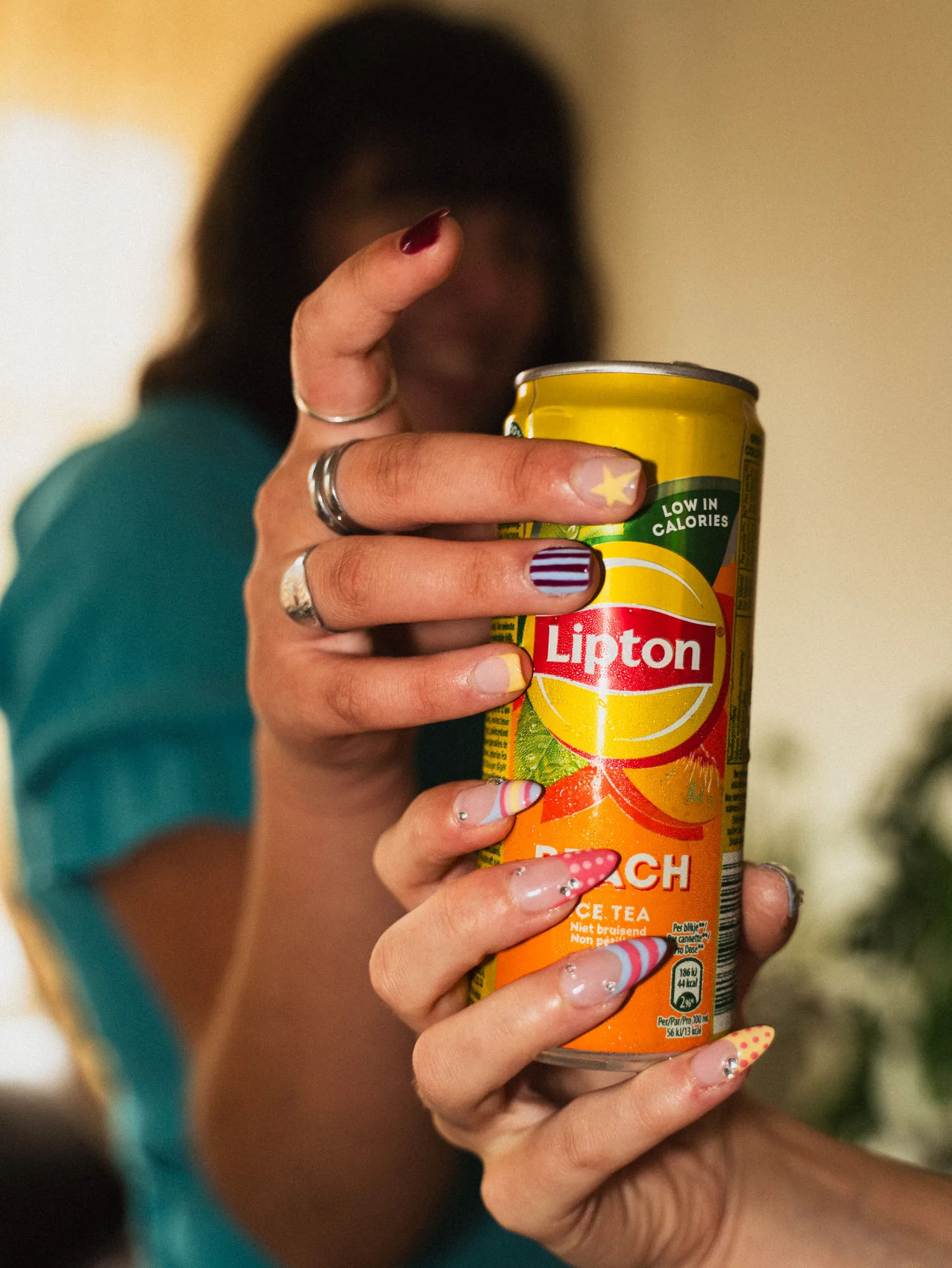 Mise en scène des ongles multicolores avec une canette de thé glacé